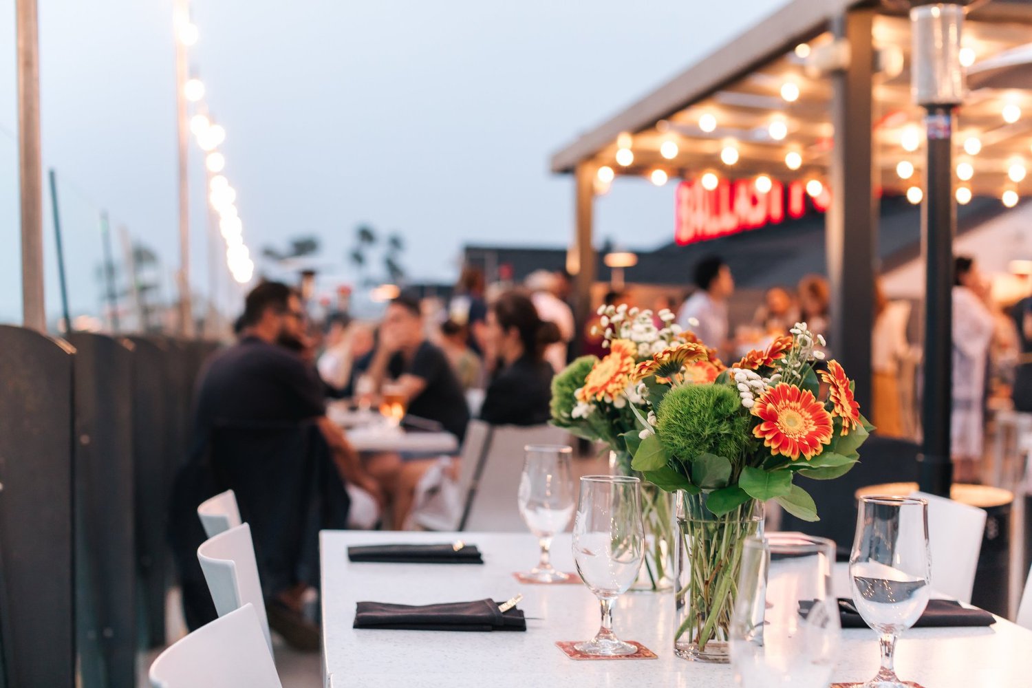 Ballast Point Brewery patio with elegant table settings, flowers, and string lights at sunset